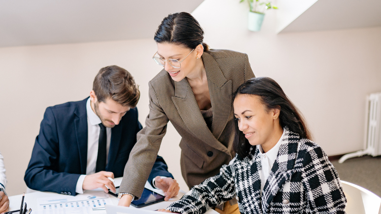 Three professionals collaborating over documents and a tablet in a modern office