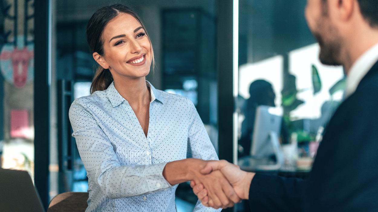 Young professional woman shaking hands with a colleague in a modern office setting