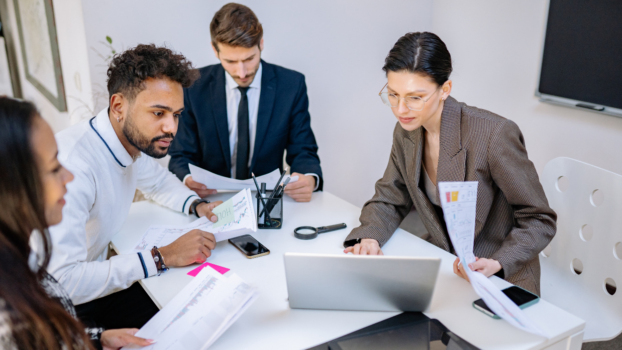 Diverse team of professionals reviewing recruitment documents and data around a table