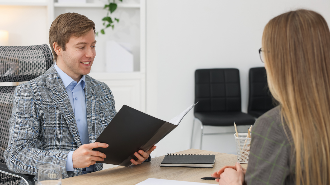 Franchise hiring manager reviewing a candidate's portfolio during a job interview in a modern office