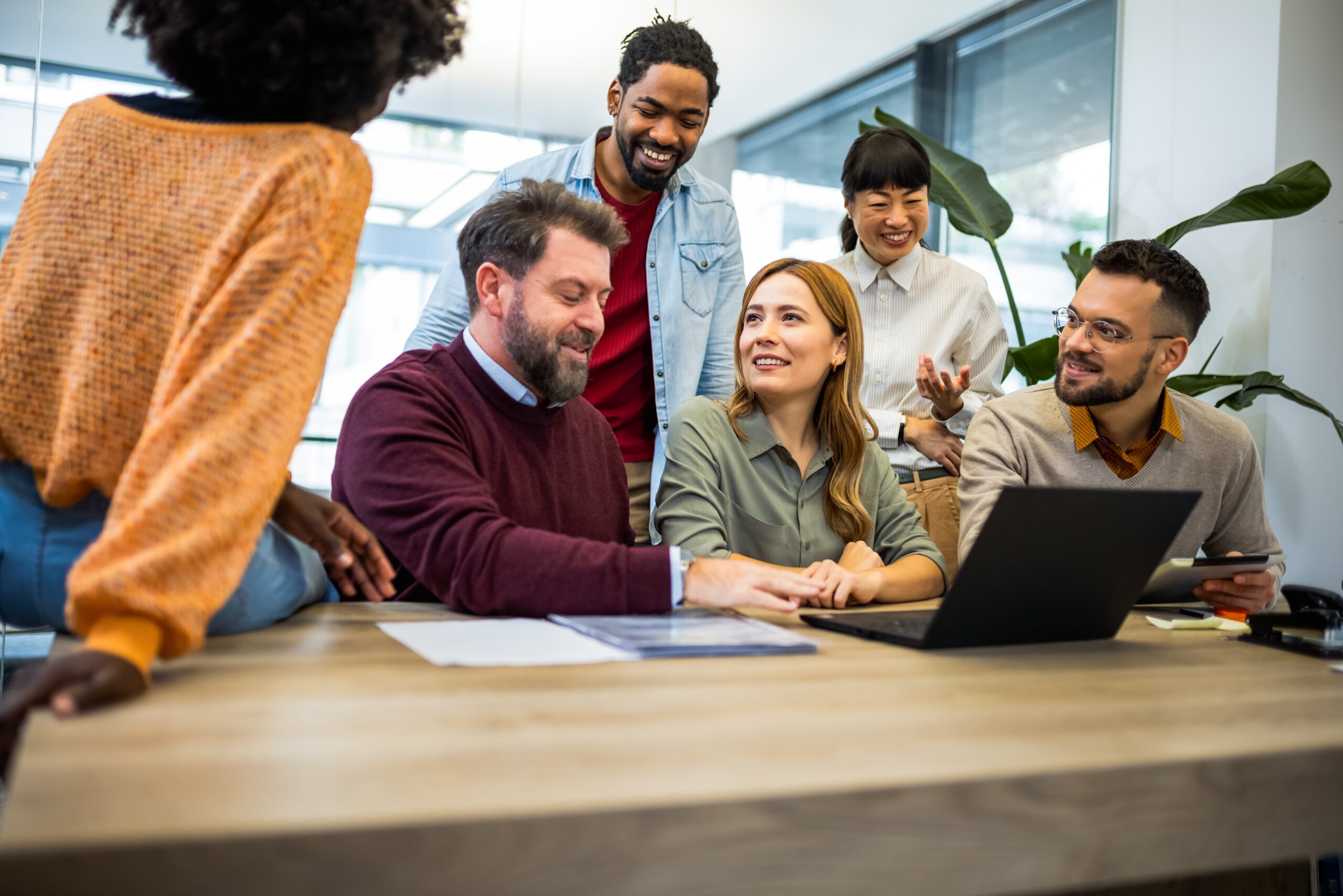 Multicultural team gathered around a laptop collaborating in a modern office