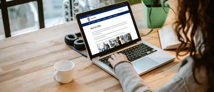 Woman using a laptop to browse the Apply Direct career site platform at a modern workspace