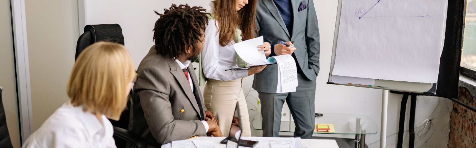 Diverse team of franchise professionals collaborating around a table with a whiteboard in a modern office